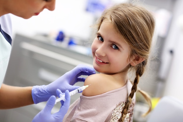 brave little girl receiving injection or vaccine with a smile