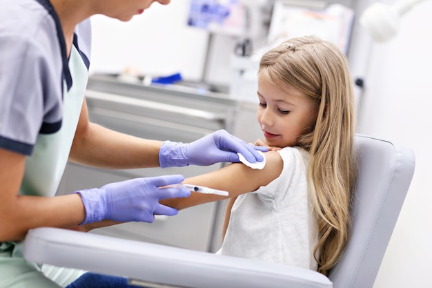 brave little girl receiving injection or vaccine with a smile