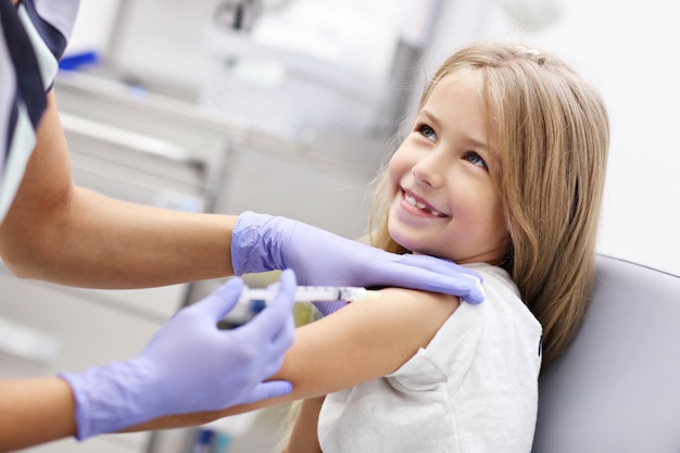 brave little girl receiving injection or vaccine with a smile