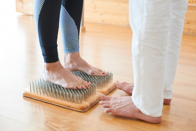 Brave woman standing on bed of nails at yoga practice