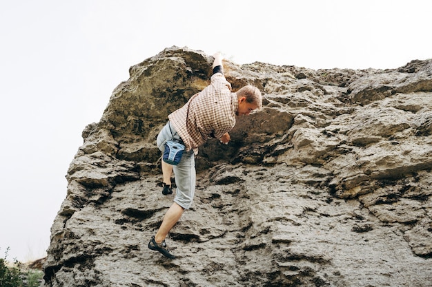 Brave young man climbs the cliff 