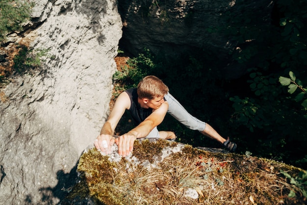 Brave young man climbs the cliff 