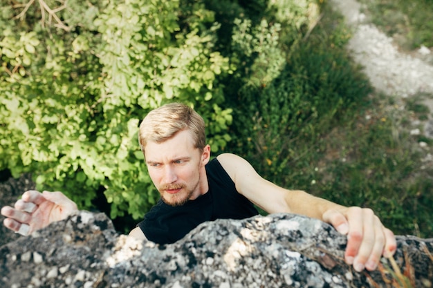 Brave young man climbs the top of the cliff