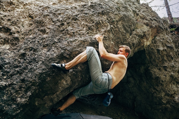 Brave young man hanging on the cliff