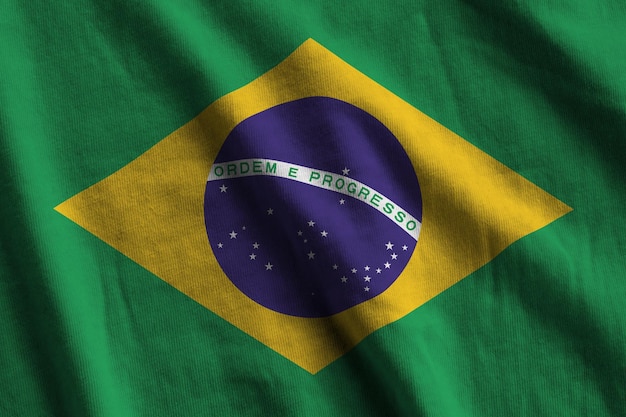 Brazil flag with big folds waving close up under the studio light indoors The official symbols and colors in banner