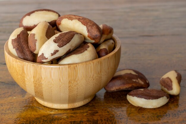 Brazil nuts in bamboo bowl on rustic wooden table.