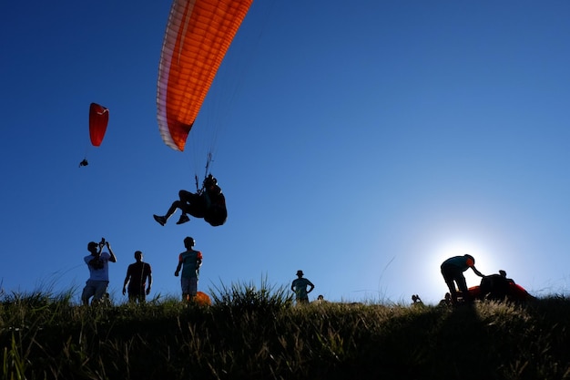 Brazil SaoPaulo Guaruja 09 February 2019 Paraglider is flying in the sky above the mountains and people looking at himThe main area for paragliding