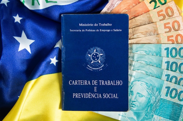 Braziliaans documentwerk en sociale zekerheid Carteira de Trabalho e Previdencia Social met Braziliaanse geldbankbiljetten en Braziliaanse vlag op de achtergrond