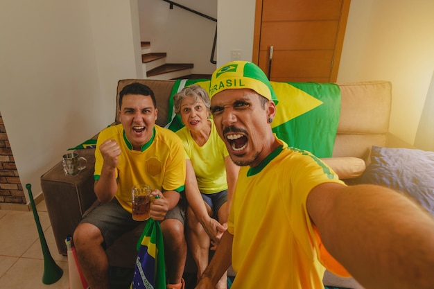 Braziliaans gemengd ras familie vieren de beker in de woonkamer kijken naar voetbalwedstrijd Familie selfie foto maken tijdens het kijken naar bekerwedstrijd