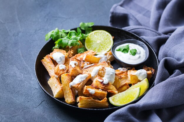 Braziliaans keukenvoedsel, Latijnse snack. Gebakken yucca, yuca, cassave, maniocasticks met koriandersaus.