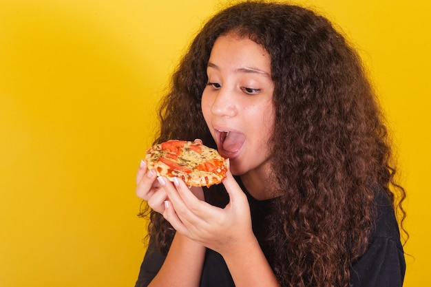 Braziliaans latijns-amerikaans meisje voor afro haar gele achtergrond klaar om heerlijke mini pizza pizza margarita pizza kaas uit te rekken kaas