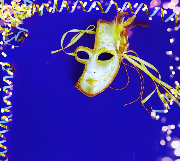 Braziliaans of Venetiaans carnaval Een helder masker op een blauwe achtergrond met een gouden serpentijn
