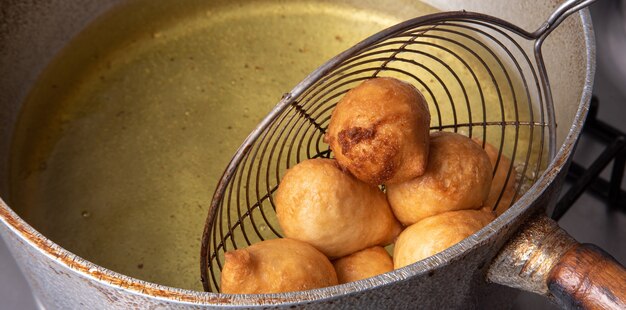 Braziliaans snoepje genaamd bolinho de chuva, afkomstig uit frituren in een pan met olie, selectieve focus.