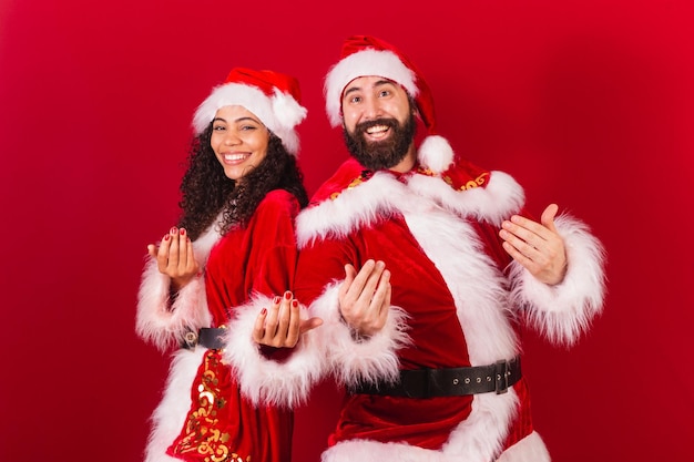 Braziliaans stel gekleed voor kerstman, mummie die belt met handen die zwarte vrouw en blanke man uitnodigen
