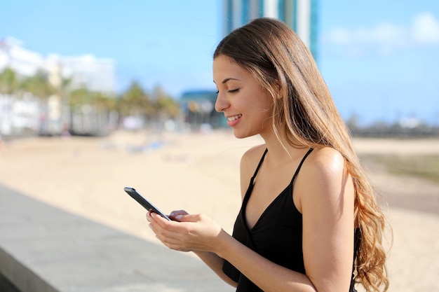 Braziliaans tienermeisje dat een smartphone gebruikt met wazig stadsstrand op de achtergrond