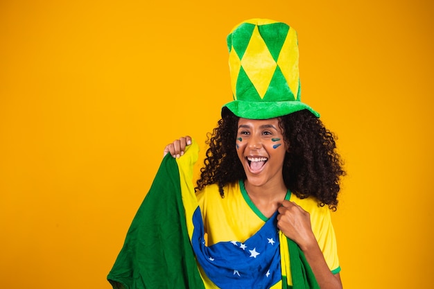 Braziliaanse aanhanger. Braziliaanse vrouw fan vieren op voetbal of voetbalwedstrijd op gele achtergrond. Brazilië kleuren.