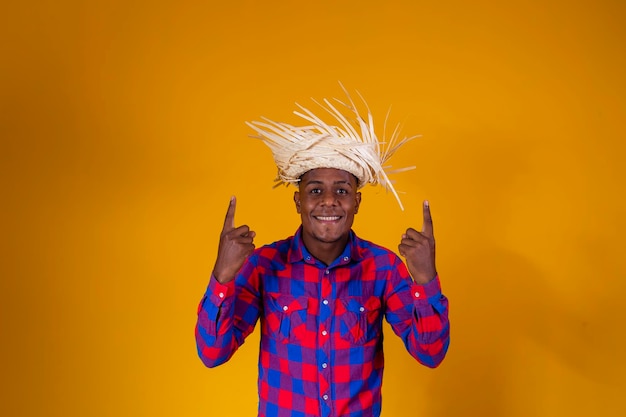 Braziliaanse afro-man met typische kleding voor de Festa Junina die naar boven wijst