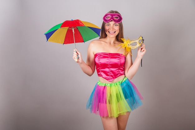 Braziliaanse blonde vrouw gekleed in roze carnaval kleding masker met frevo paraplu en geel masker