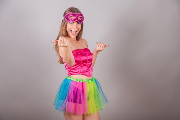 Braziliaanse blonde vrouw gekleed in roze carnavalskleding met maskers komt uitnodigend met je handen