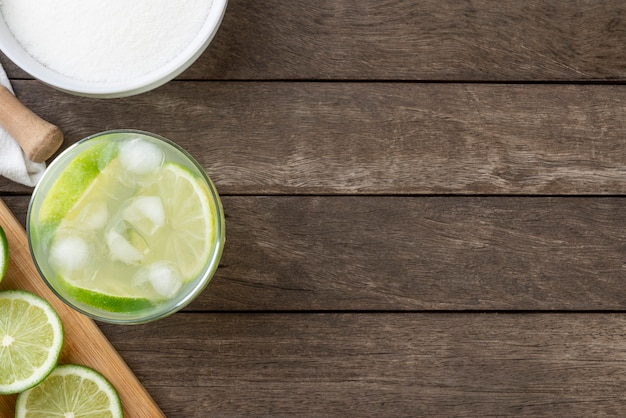 Braziliaanse citroencaipirinha in een glas met ijs met fruitplakken over houten raad met exemplaarruimte