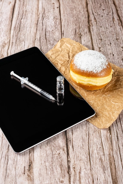 Braziliaanse crème donuts naast een spuit en ampul met insuline en een tablet