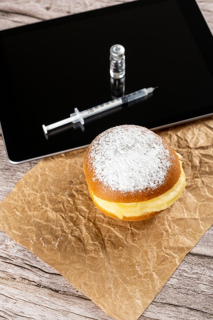 Braziliaanse crème donuts naast een spuit en een ampul insuline op een tabletverticaal