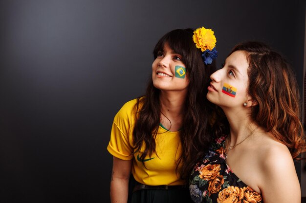 Braziliaanse en Ecuadoriaanse dames met lichaamskunst op hun gezicht kijken verrast vooruit Kleurrijk schilderij Selectieve focus