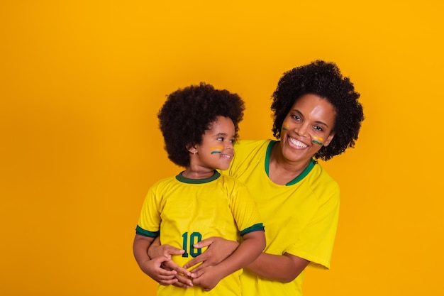 Braziliaanse familie juicht samen Fans vieren op gele achtergrond Gezichten geschilderd en juichen met de gele tshirt