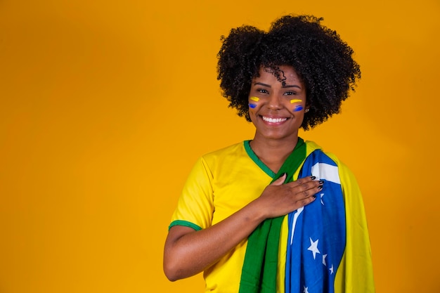 Braziliaanse fan met Braziliaanse vlag in een portret Braziliaanse fan die voetbal of voetbalwedstrijd viert op gele achtergrond Kleuren van BrazilWorld Cup