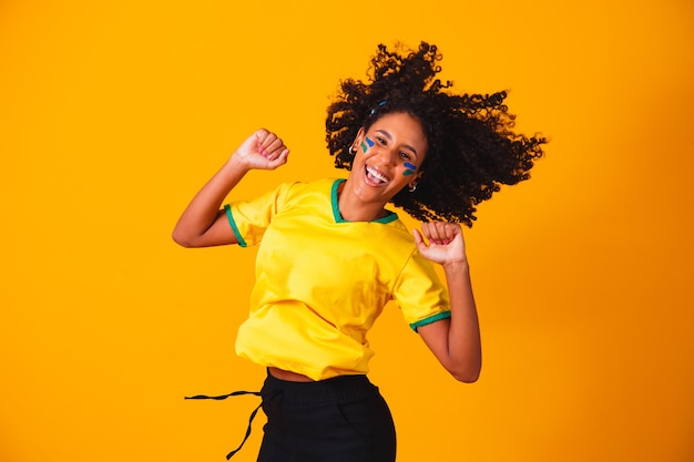 Braziliaanse fan. springen om te vieren, braziliaanse fan viert voetbal of voetbalwedstrijd op gele achtergrond. kleuren van brazilië.