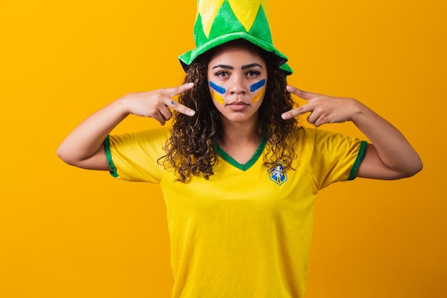 Braziliaanse fan. verf gebruiken als make-up, Braziliaanse fan die voetbal of voetbalwedstrijd viert op gele achtergrond. Kleuren van Brazilië.