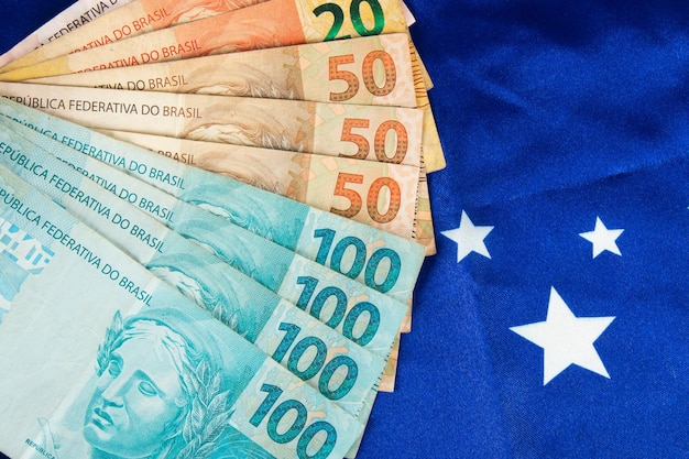 Foto braziliaanse geldbankbiljetten met braziliaanse vlag op de achtergrond