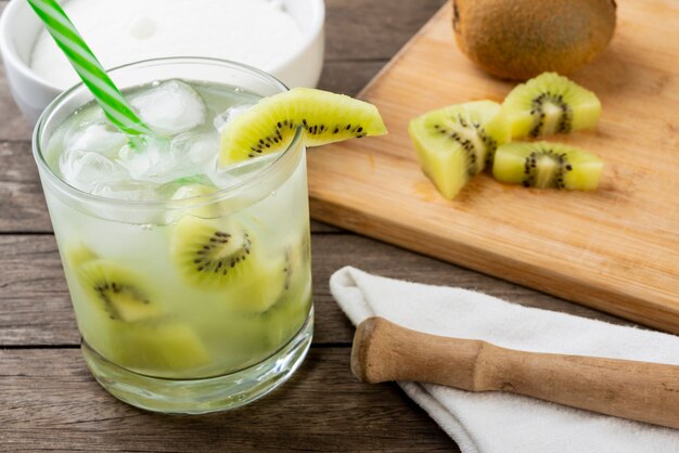 Braziliaanse kiwicaipirinha in een glas met ijs met fruitplakken over houten raad