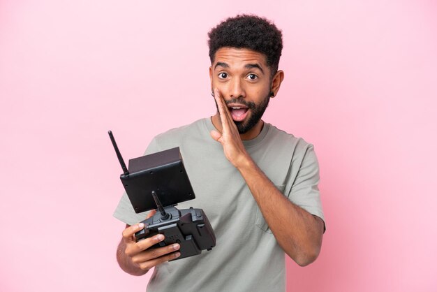 Braziliaanse man met een drone-afstandsbediening geïsoleerd op een roze achtergrond die iets fluistert