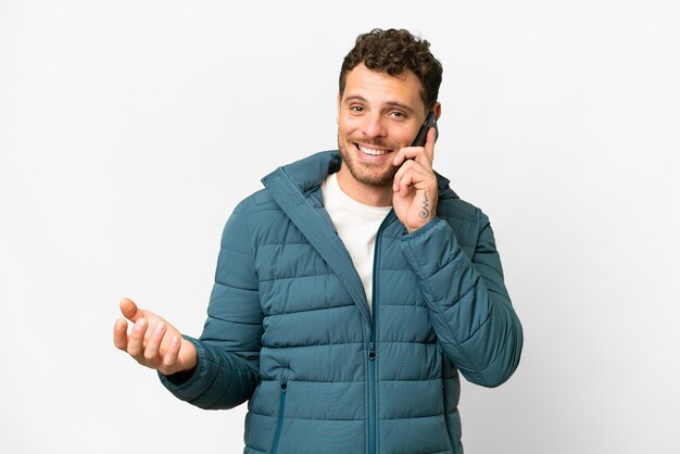 Braziliaanse man over geïsoleerde witte achtergrond die een gesprek voert met de mobiele telefoon met iemand