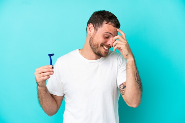 Braziliaanse man scheert zijn baard geïsoleerd op blauwe achtergrond lachen