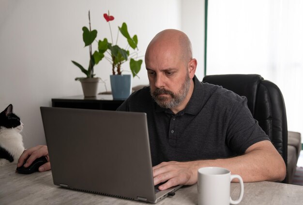 Braziliaanse man van middelbare leeftijd die een laptop gebruikt die thuis werkt