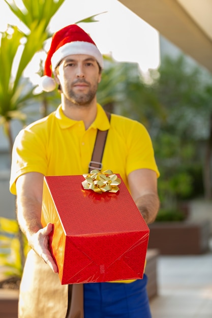 Braziliaanse postbode verkleed als kerstman die een geschenk levert. Online aankoop wordt bezorgd.