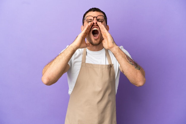 Braziliaanse restaurantkelner over geïsoleerde paarse achtergrond die iets schreeuwt en aankondigt