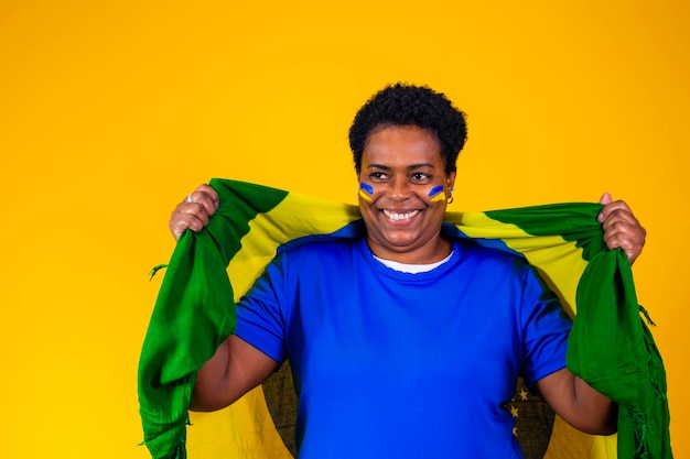 Braziliaanse supporter braziliaanse vrouw fan viert op voetbal of voetbalwedstrijd op gele achtergrond brazilië kleuren