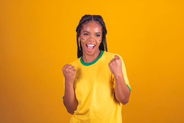 Braziliaanse supporter Braziliaanse vrouw fan viert op voetbal of voetbalwedstrijd op gele achtergrond Brazilië kleuren