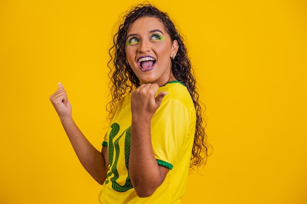 Braziliaanse supporter Braziliaanse vrouw fan viert op voetbal of voetbalwedstrijd op gele achtergrond Brazilië kleuren