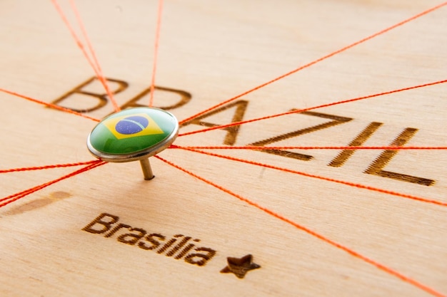 Braziliaanse vlag op de pushpin en rode draden op de houten kaart