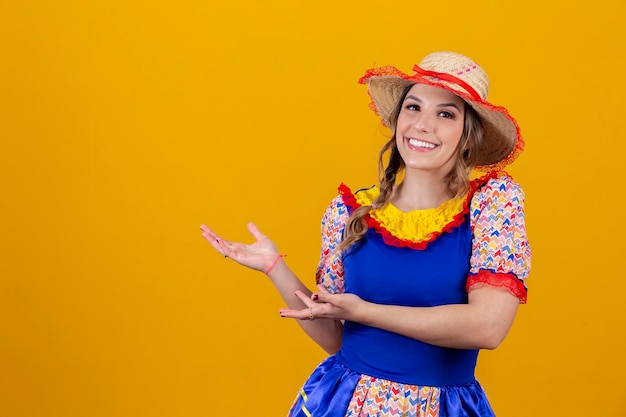 Braziliaanse vrouw die typische kleding draagt voor festa junina en naar de zijkant wijst op vrije ruimte voor tekst