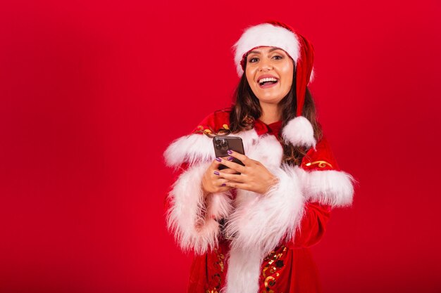 Braziliaanse vrouw gekleed in kerstkleding Santa Claus die smartphone vasthoudt en typt