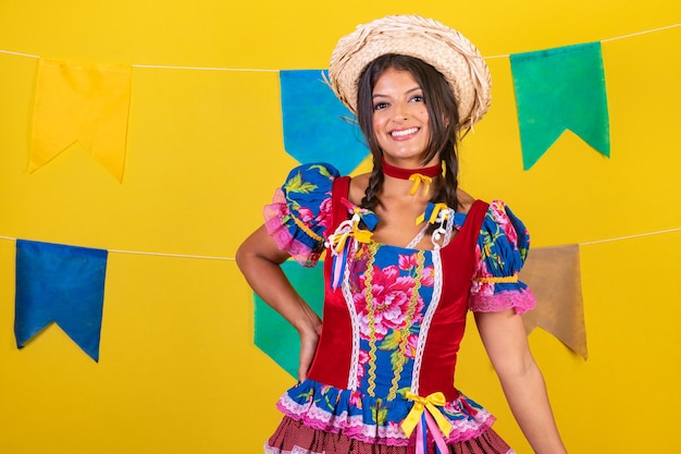 Braziliaanse vrouw met kleding van festa de sao joao festa junina op gele achtergrond met vlaggen