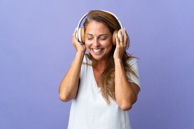 Braziliaanse vrouw van middelbare leeftijd geïsoleerd op paarse muur luisteren muziek