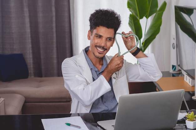 Braziliaanse zwarte arts of dierenarts die thuis werkt Jonge man doet thuiskantoor overdag aan bureau met laptop