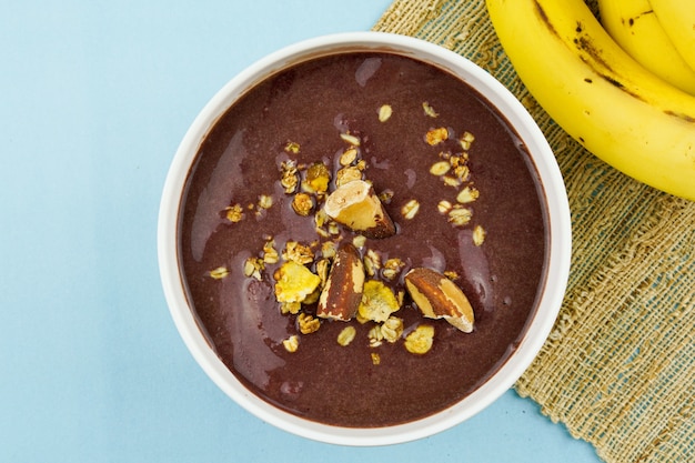 Brazilian aÃÂ§ai in a white bowl with banana, granola and chestnuts.