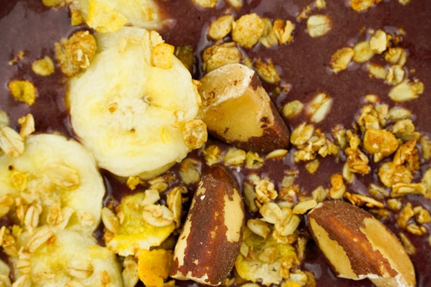 Brazilian aÃÂ§ai in a white bowl with banana, granola and chestnuts.